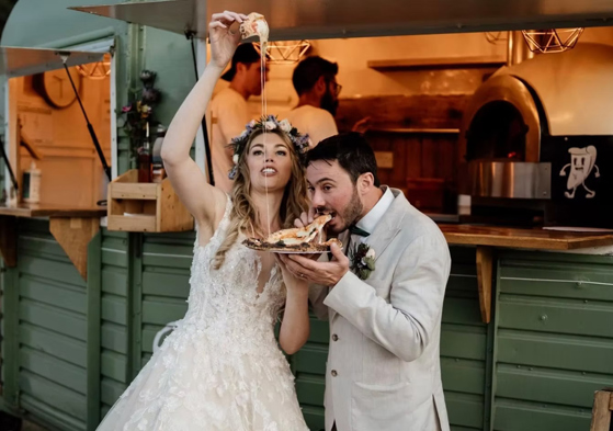 Bride and groom eating pizza in front of Dough Man's Land horsebox